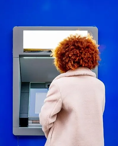 Frau bedient einen Bankautomat